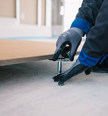 Hände mit Arbeitshandschuhen bei der Verlegung eines Bodens